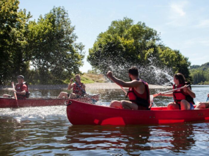 Un groupe de personnes faisant du canoë-kayak sur la Dordogne s’amuse en se lançant de l’eau.